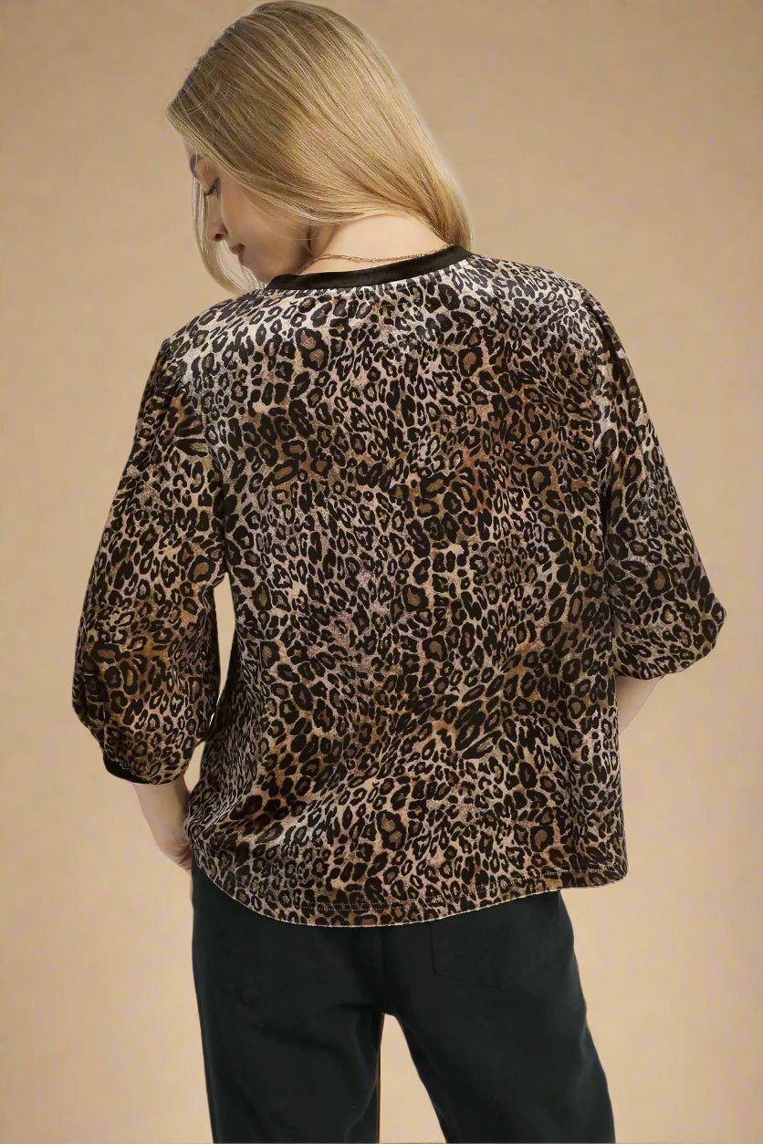Person wearing a leopard print top on a white background