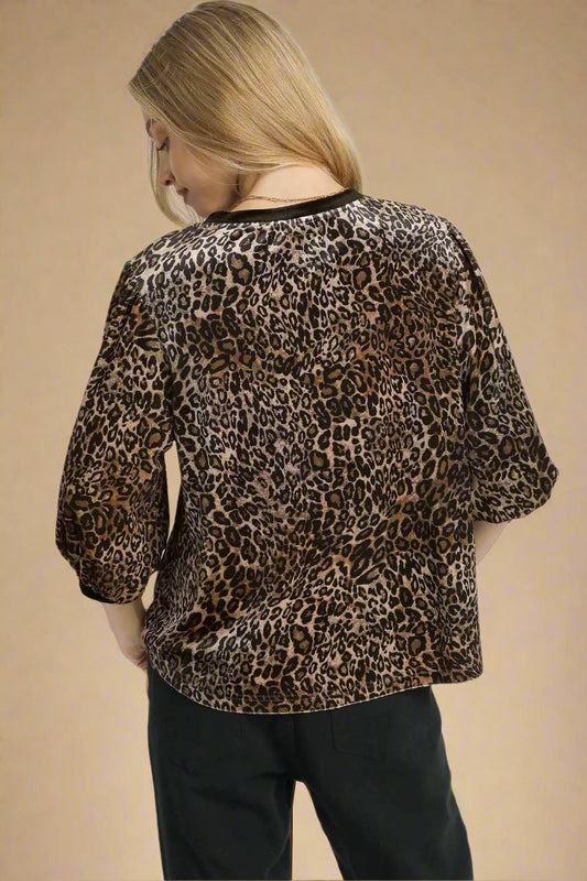 Person wearing a leopard print top on a white background