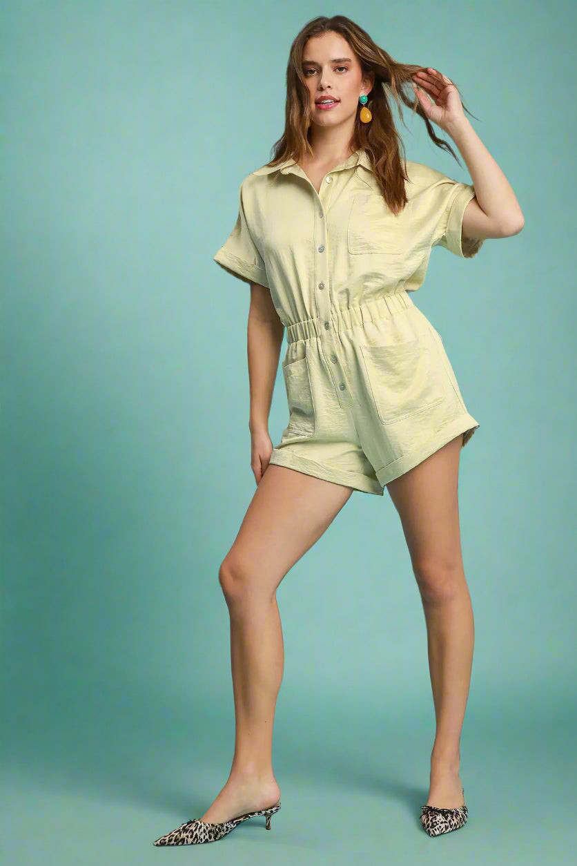 Woman wearing a light green romper against a teal background