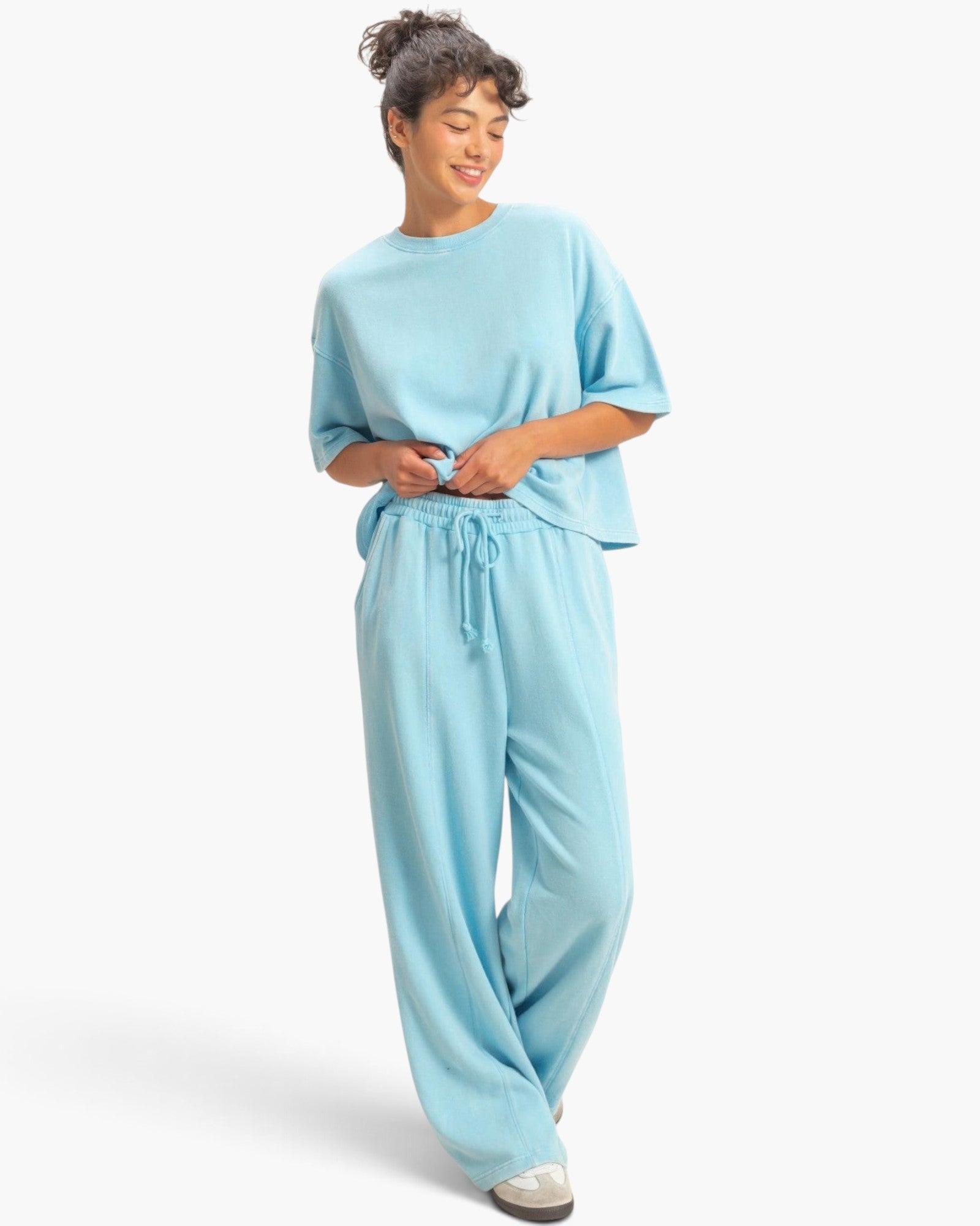 Beach Rose Co. light blue acid wash French terry wide-leg pants with drawstring waist worn by a smiling model