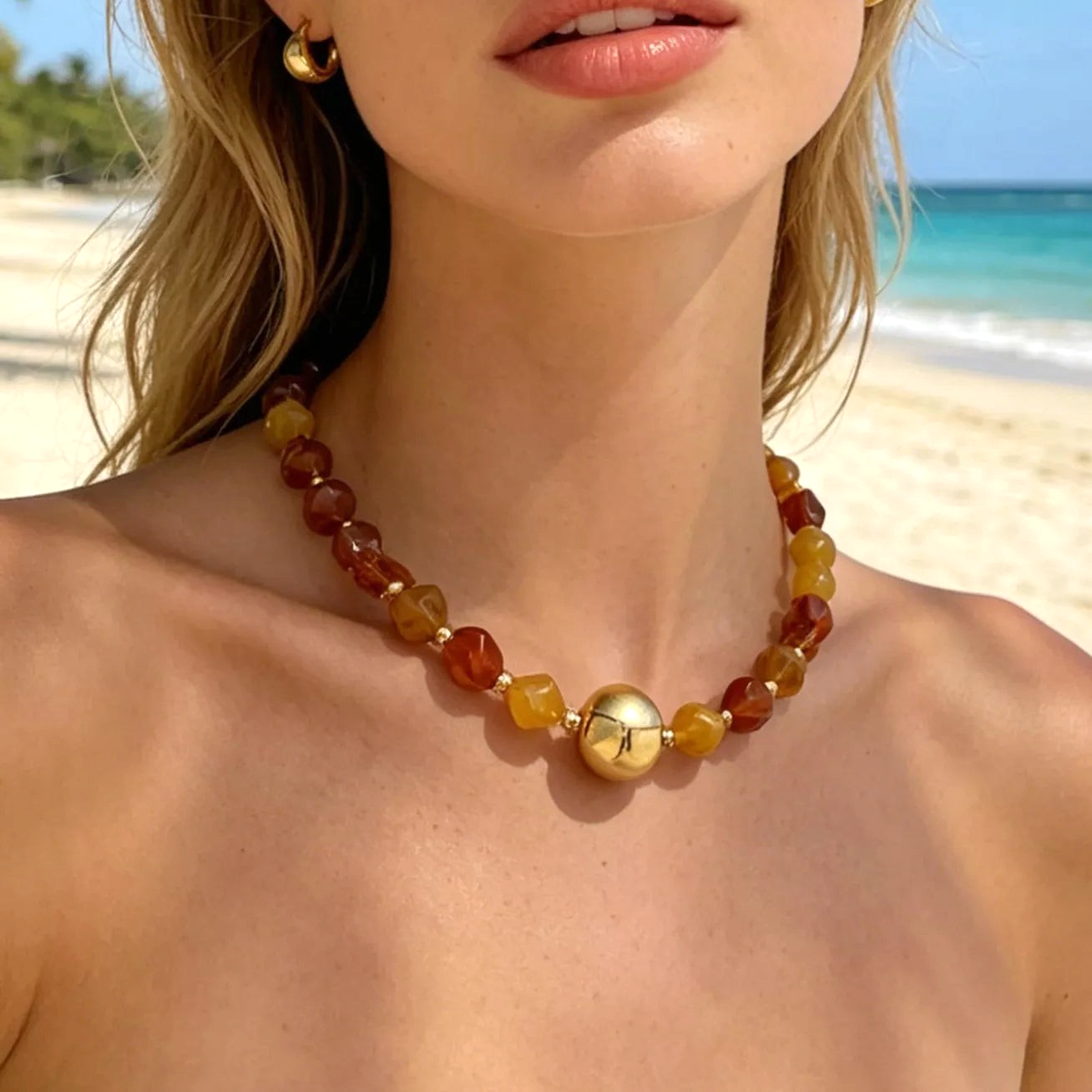 Beach Rose Co. 18K gold-plated necklace featuring amber-tone resin beads and a large polished gold center bead.