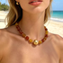 Beach Rose Co. 18K gold-plated necklace featuring amber-tone resin beads and a large polished gold center bead.