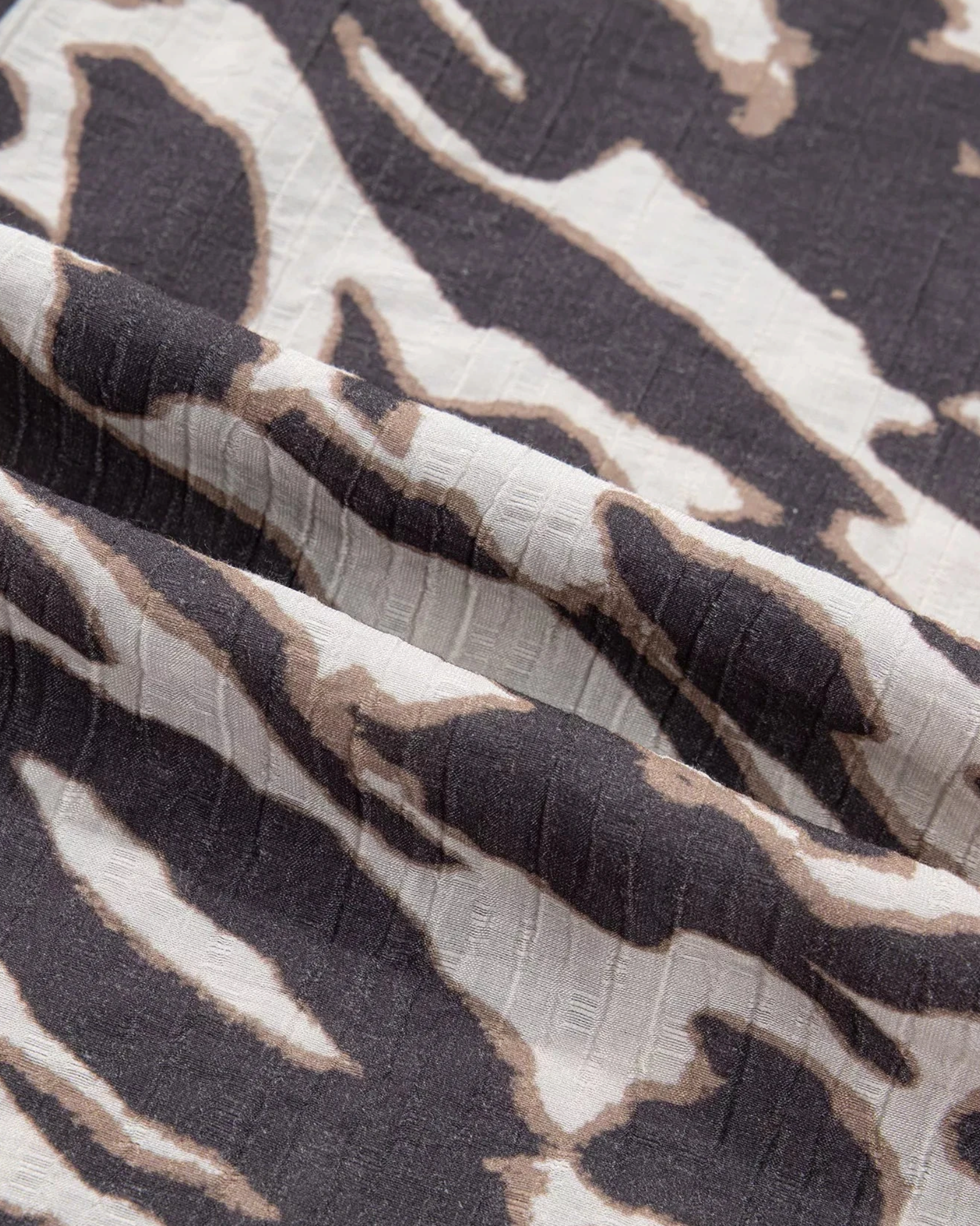 Close-up of Beach Rose Co. charcoal and cream viscose blend fabric with a textured mixed animal print pattern.