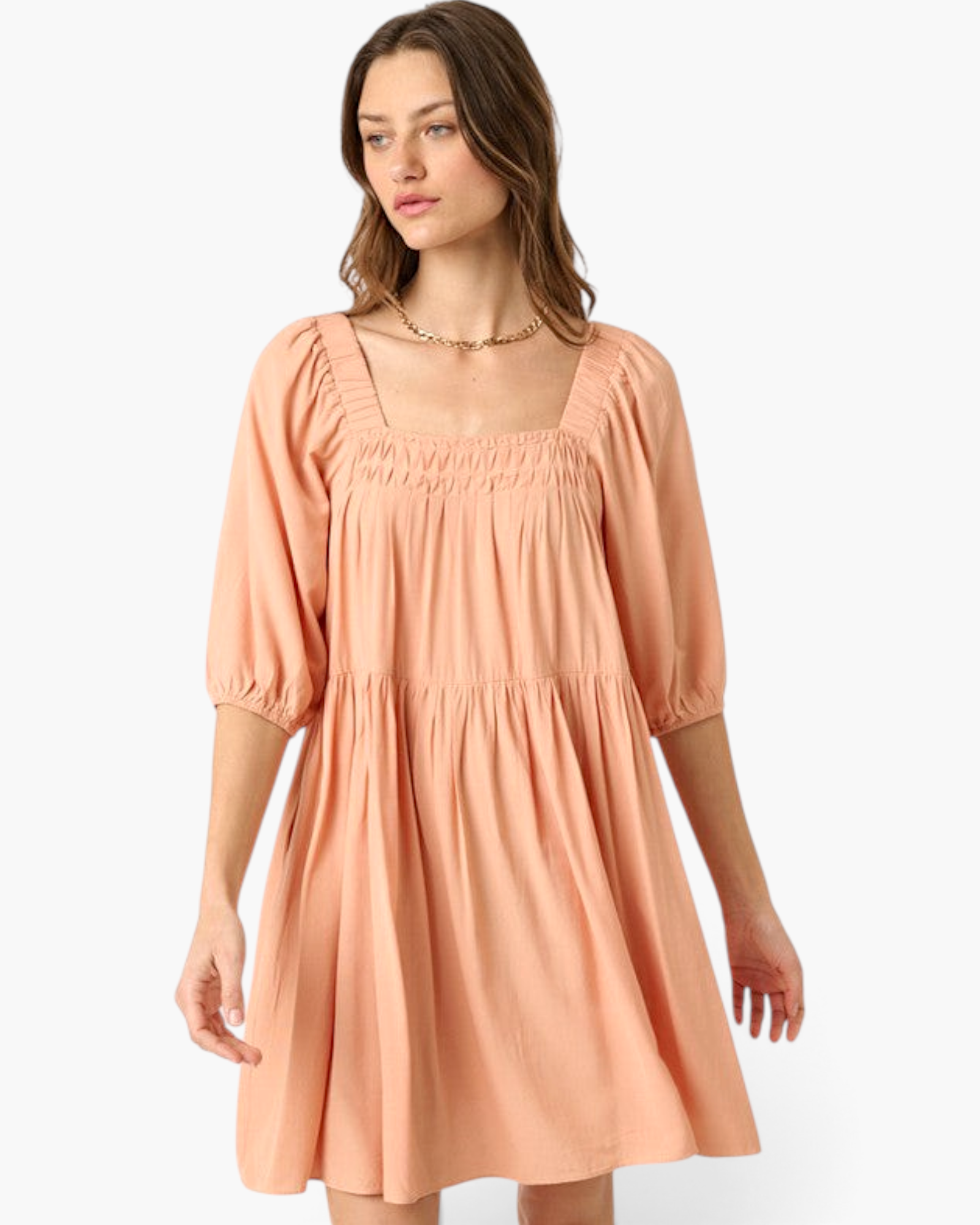 Beach Rose Co. apricot babydoll dress with a smocked square neckline and elbow-length puff sleeves on a model.