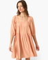 Beach Rose Co. apricot babydoll dress with a smocked square neckline and elbow-length puff sleeves on a model.