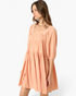 Beach Rose Co. apricot babydoll mini dress with a smocked square neckline and puff sleeves on a model