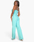 Beach Rose Co. aqua V-neck camisole jumpsuit on a model, featuring a sleek stretch knit fabric and wide-leg silhouette.