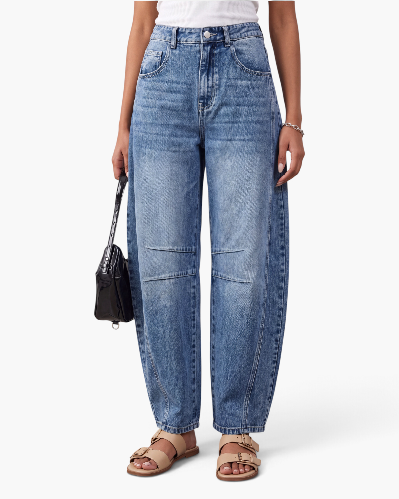 Beach Rose Co. blue denim barrel leg jeans featuring knee darts and curved seams worn with beige sandals