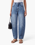 Beach Rose Co. blue denim barrel leg jeans featuring knee darts and curved seams worn with beige sandals