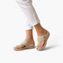 Beach Rose Co. beige thong wedge sandals with decorative cutout details and gold-tone accents worn with white pants.