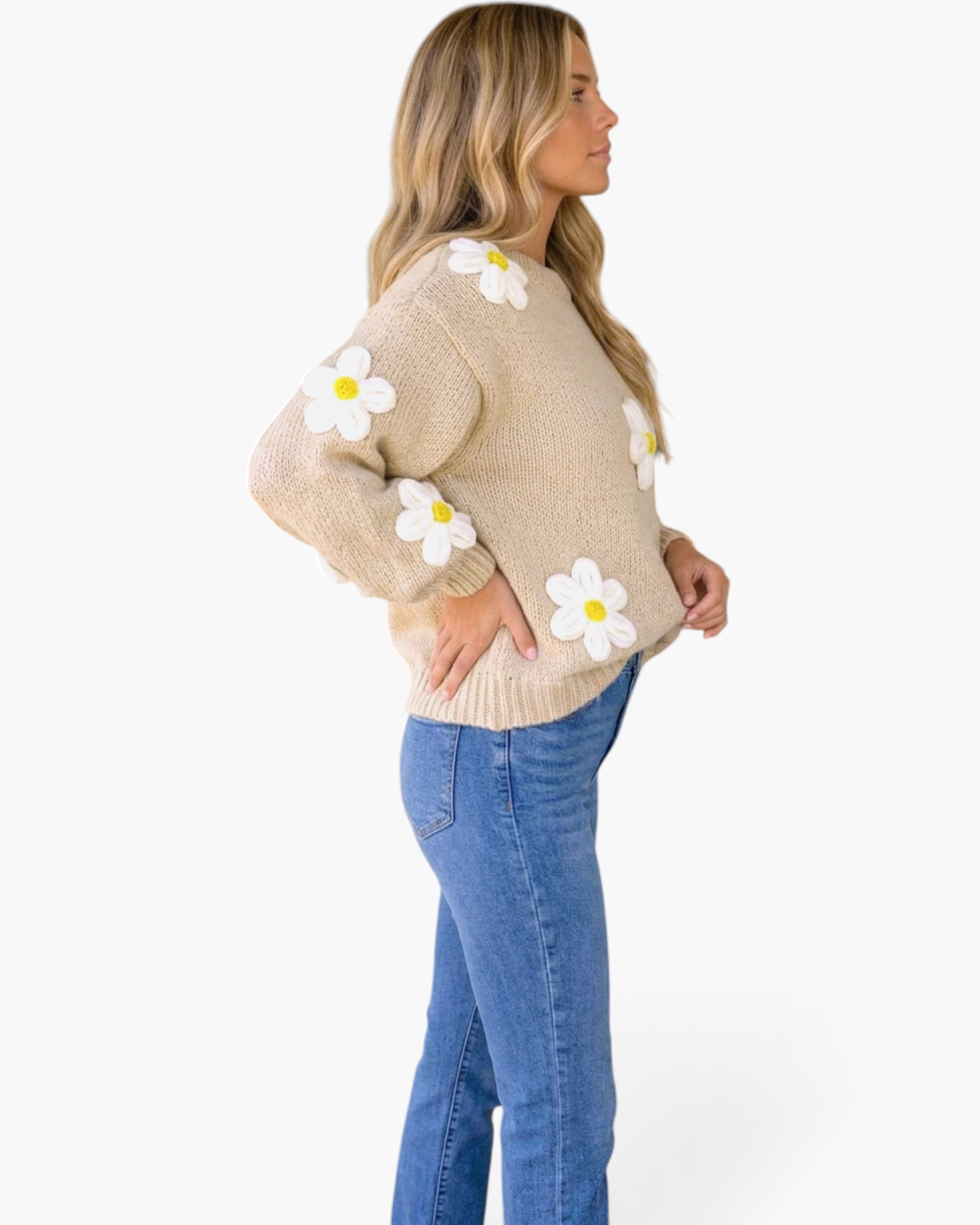 Beach Rose Co. beige knit sweater with dimensional white daisy appliqués and yellow centers worn with blue jeans