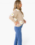 Beach Rose Co. beige knit sweater with dimensional white daisy appliqués and yellow centers worn with blue jeans