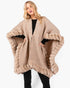 Beach Rose Co. beige knit cape with plush faux fur trim and front clasp closure worn by a blonde model
