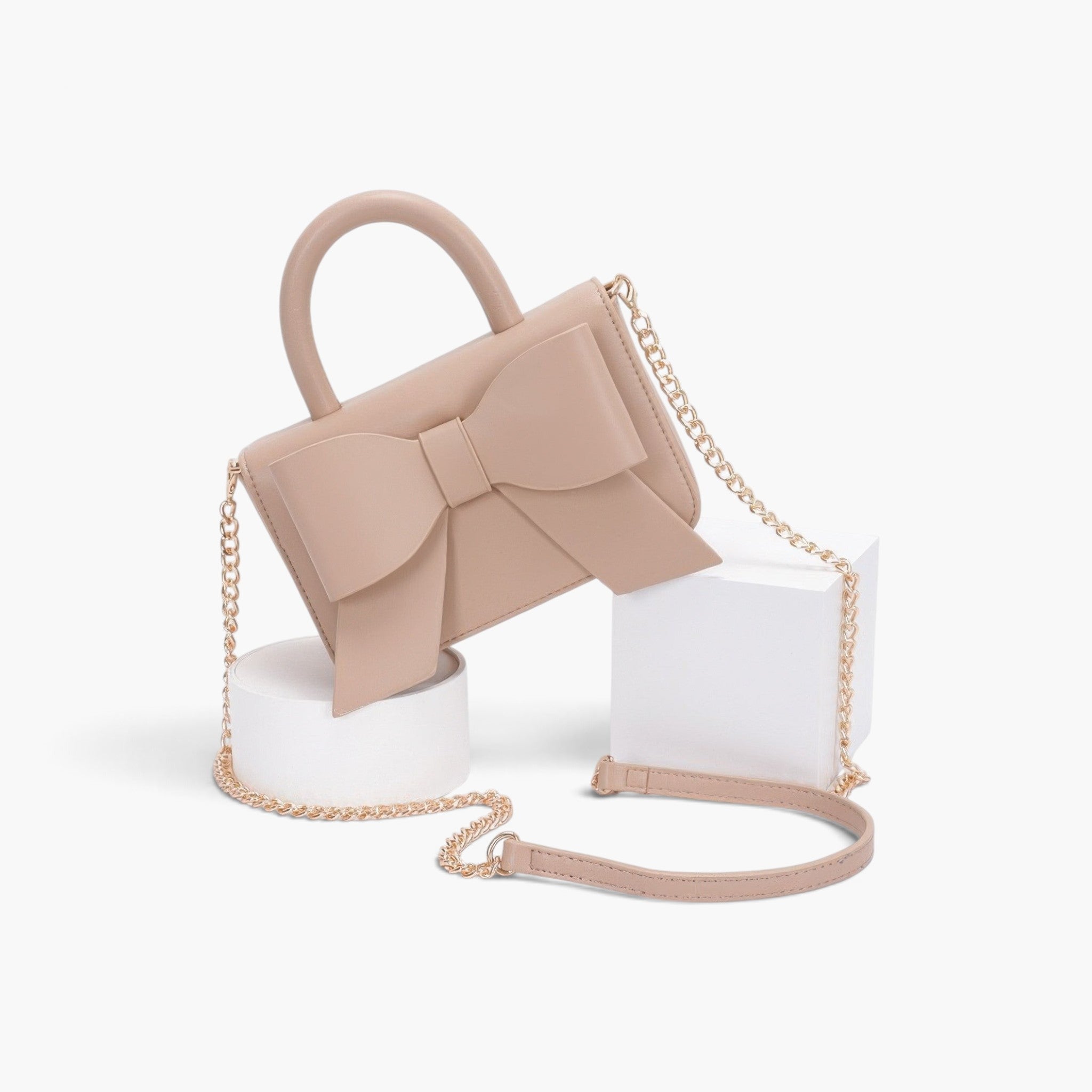 Beach Rose Co. beige faux leather handbag with a decorative bow, top handle, and gold chain shoulder strap.