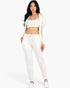 Beach Rose Co. beige French terry three-piece set with a cropped cami, zip-up jacket, and tapered joggers on a model.