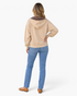 Beach Rose Co. beige zip-up hoodie with brown polka dot hood lining, worn with blue jeans, back view.