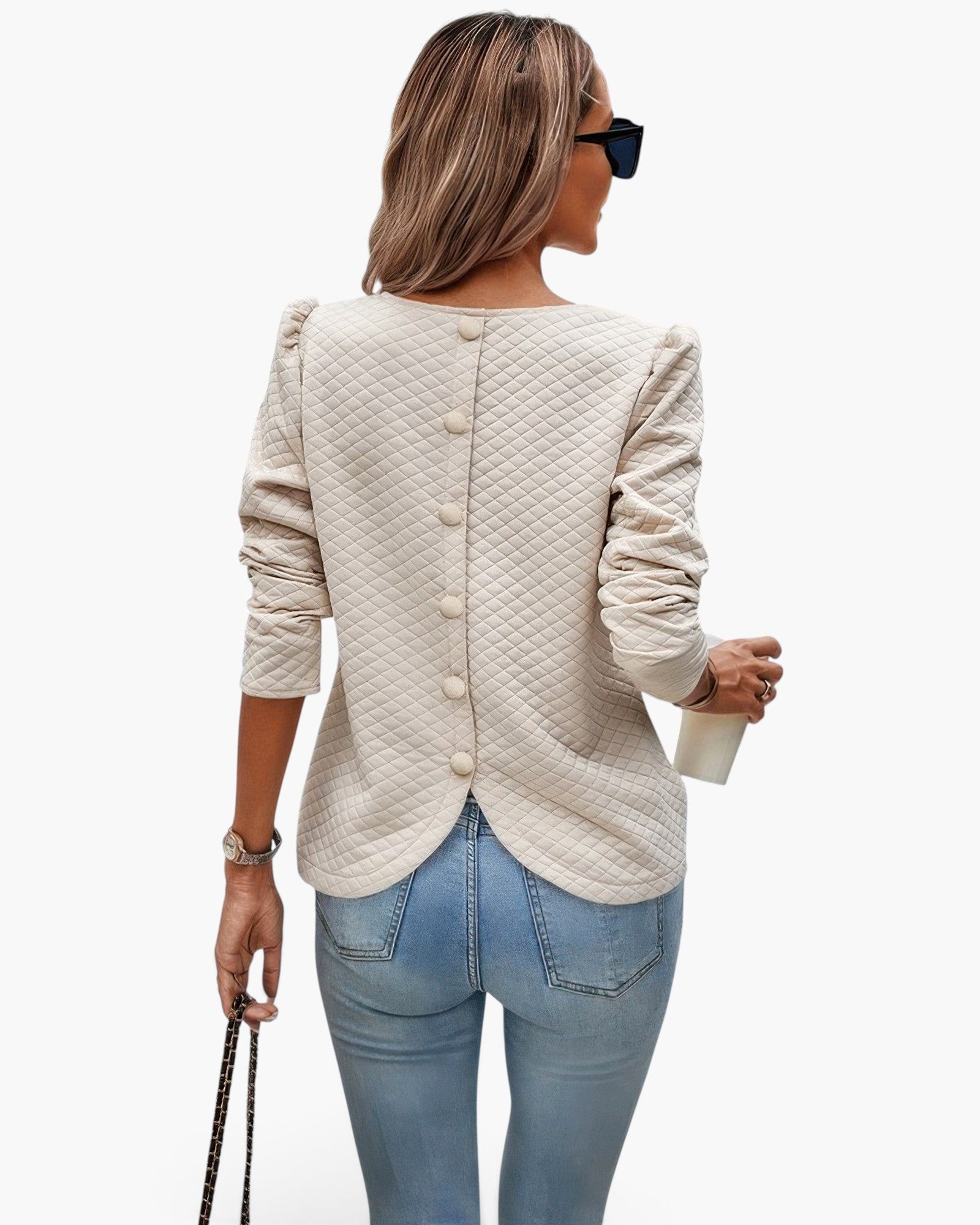 Beach Rose Co. beige quilted crewneck pullover with a button-down back and ruffled shoulder detail worn with jeans.