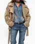 Beach Rose Co. beige short trench jacket with double-breasted front, wrap collar, and buckled belt over denim outfit.