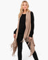 Beach Rose Co. beige open-front knit vest with embossed dotted lines and tassel fringe worn over a black outfit.
