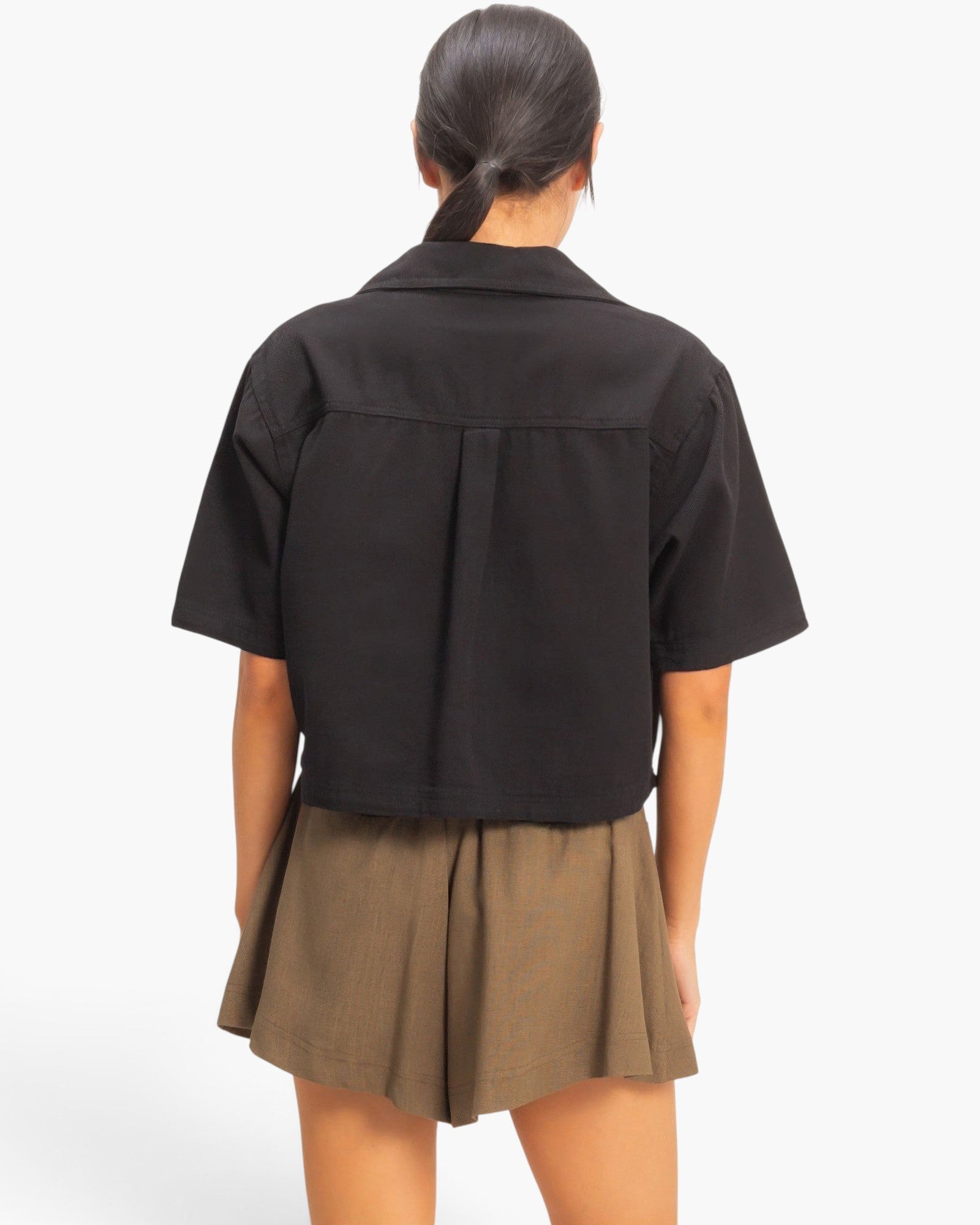 Back view of a model wearing a Beach Rose Co. black cotton collared cropped top with short sleeves