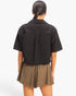 Back view of a model wearing a Beach Rose Co. black cotton collared cropped top with short sleeves
