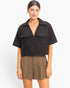 Beach Rose Co. black cotton cropped top with a structured collar, deep V-neck, and two front flap pockets.