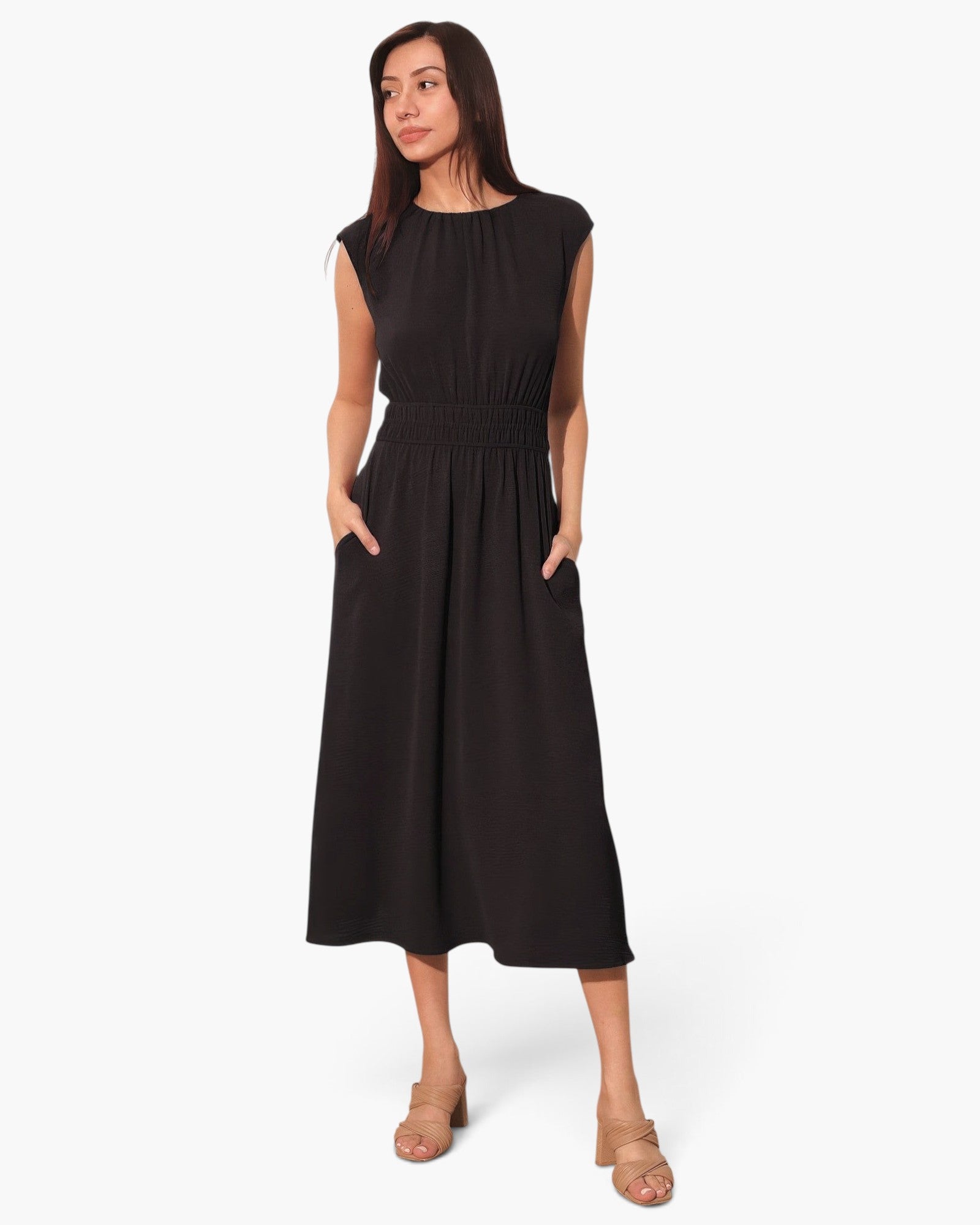 Beach Rose Co. black matte crepe midi dress with ruched elastic waist and pockets worn by a model in beige heels.