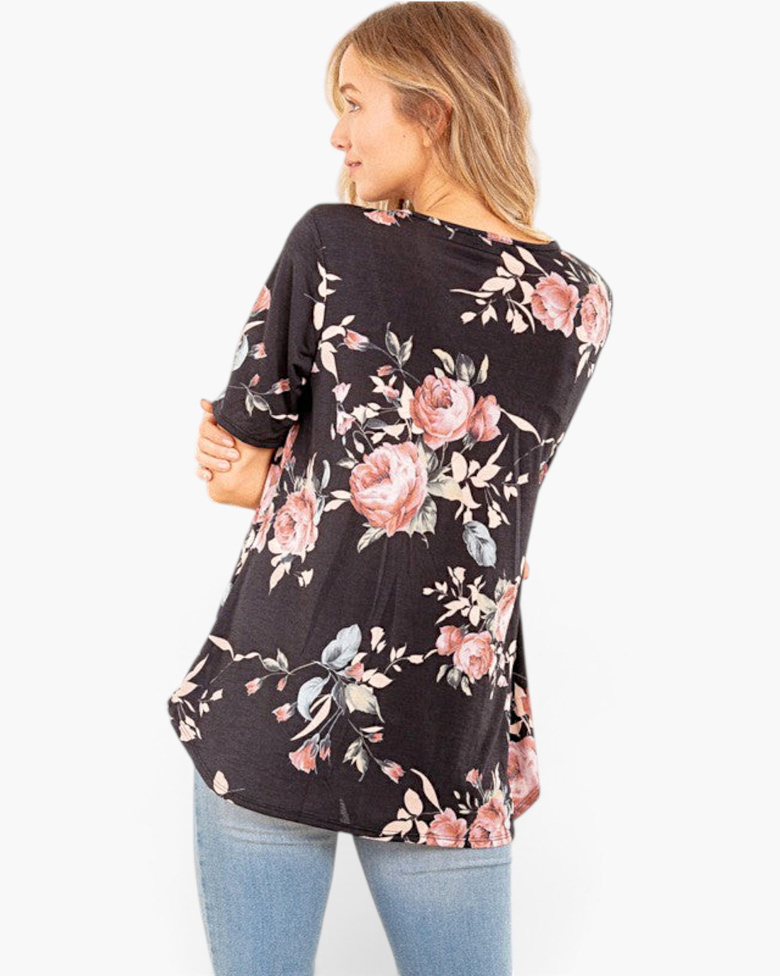 Beach Rose Co. black floral babydoll top with short sleeves and a curved hem worn by a woman from a back view