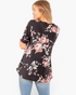 Beach Rose Co. black floral babydoll top with short sleeves and a curved hem worn by a woman from a back view