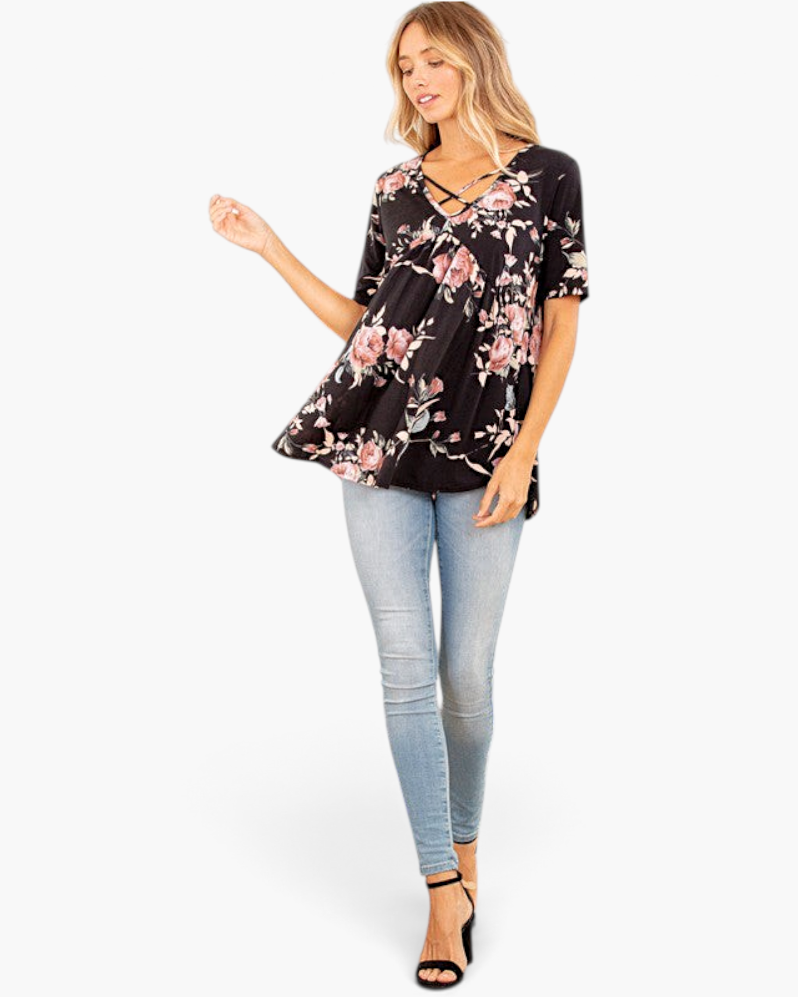 Beach Rose Co. black floral babydoll top with a crisscross V-neckline worn by a model with light blue skinny jeans