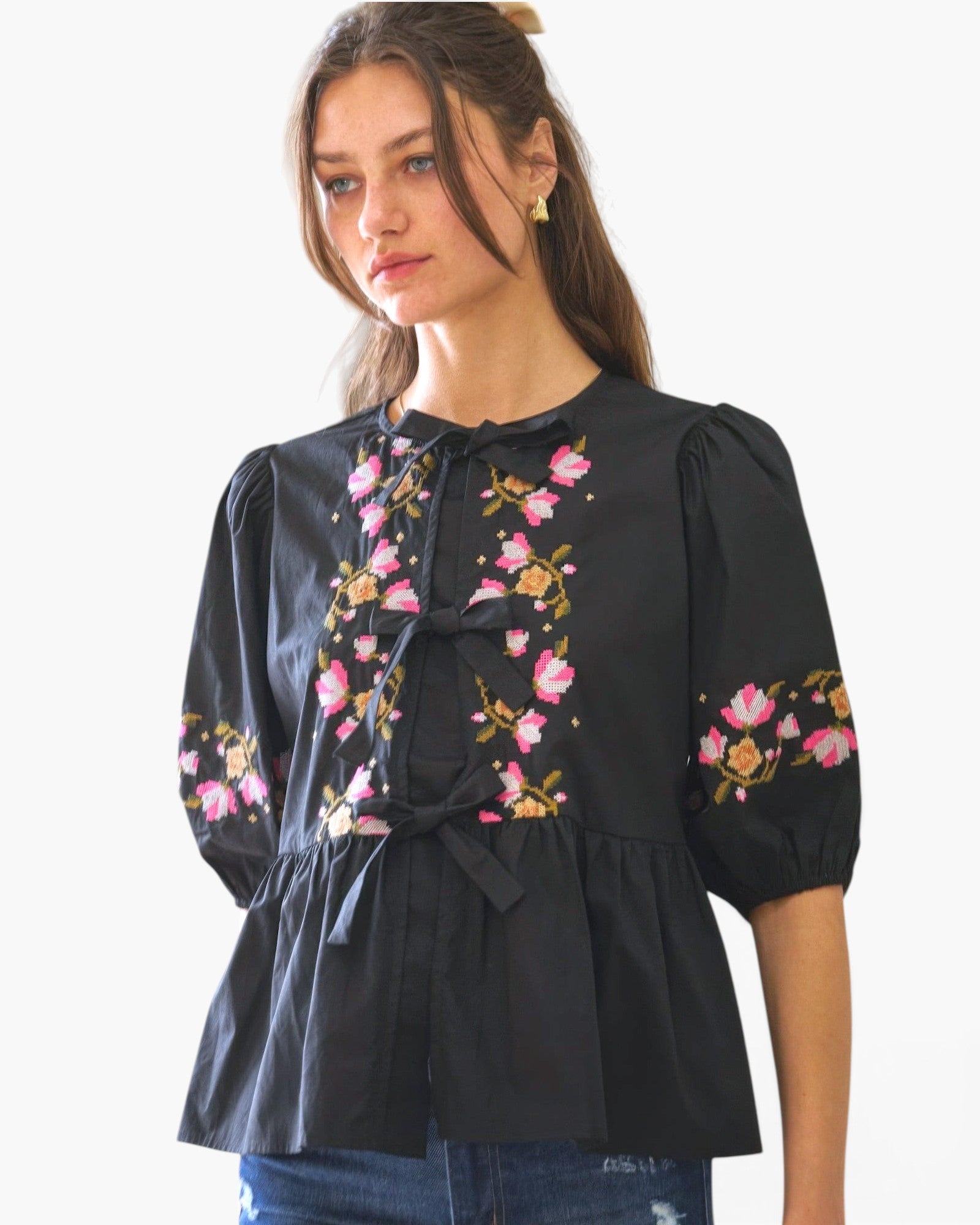 Beach Rose Co. black poplin blouse with pink and yellow floral embroidery and front ribbon ties on a model