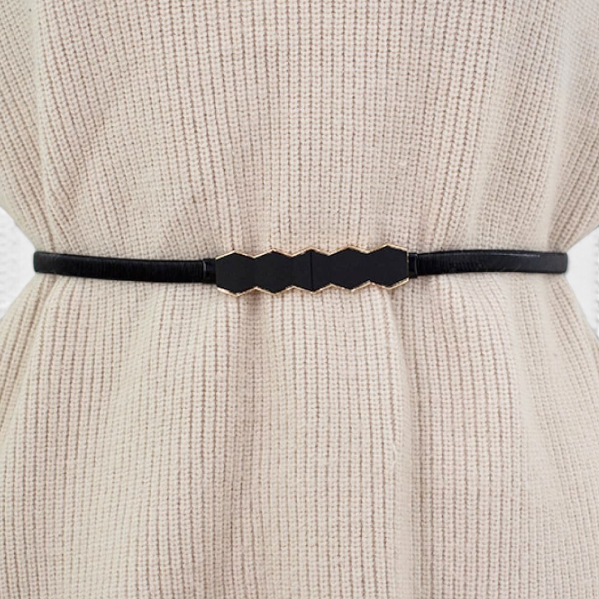 Beach Rose Co. skinny black metal waist belt featuring a geometric hexagon buckle worn over a beige ribbed sweater.