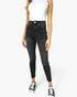 Beach Rose Co. high rise tummy control skinny jeans in washed black denim worn with a white tank top and sneakers.
