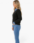 Beach Rose Co. black knit sweater with denim collar and cuffs worn by a blonde model in profile view.