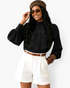 Beach Rose Co. black blouse with ornate lace overlay, high neckline, and balloon sleeves worn with white shorts