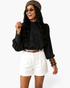 Beach Rose Co. black blouse with ornate lace overlay, high neckline, and balloon sleeves worn with white shorts