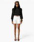Beach Rose Co. black blouse with ornate lace overlay, high neckline, and balloon sleeves worn with white shorts.