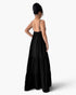 A woman shown from the back wearing a long black spaghetti-strap maxi dress with a tiered skirt, photographed against a clean white studio background.