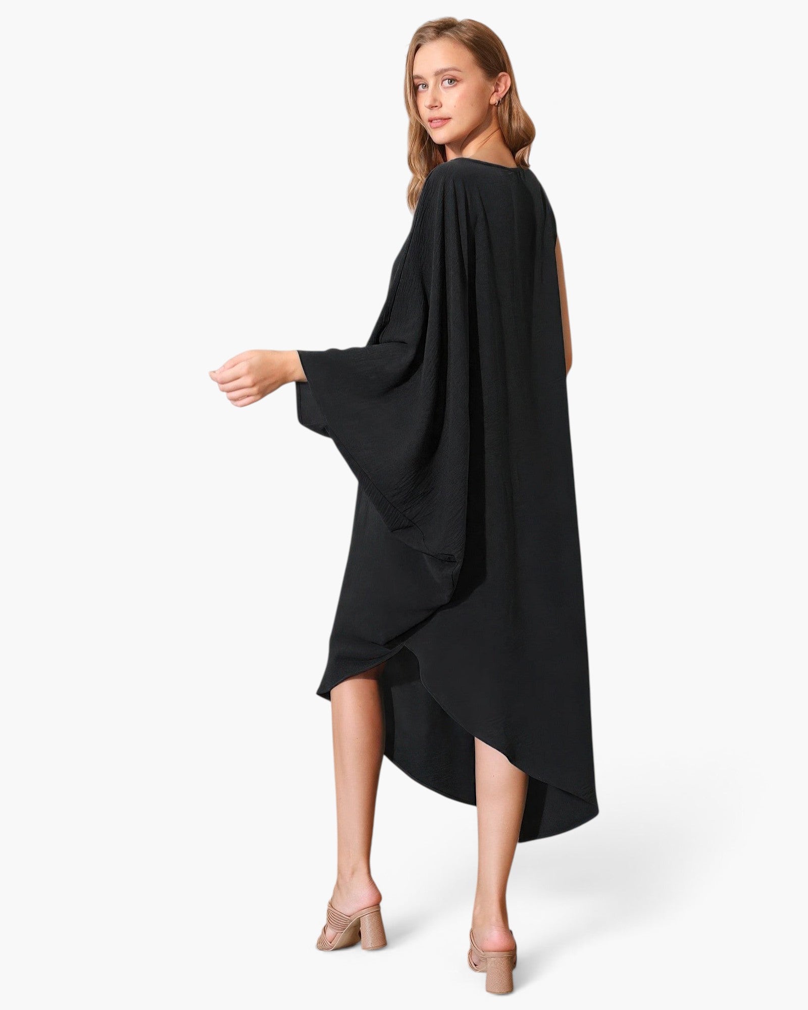 Beach Rose Co. black matte crepe one-sleeve dress with an asymmetrical hem worn by a model on a white background.