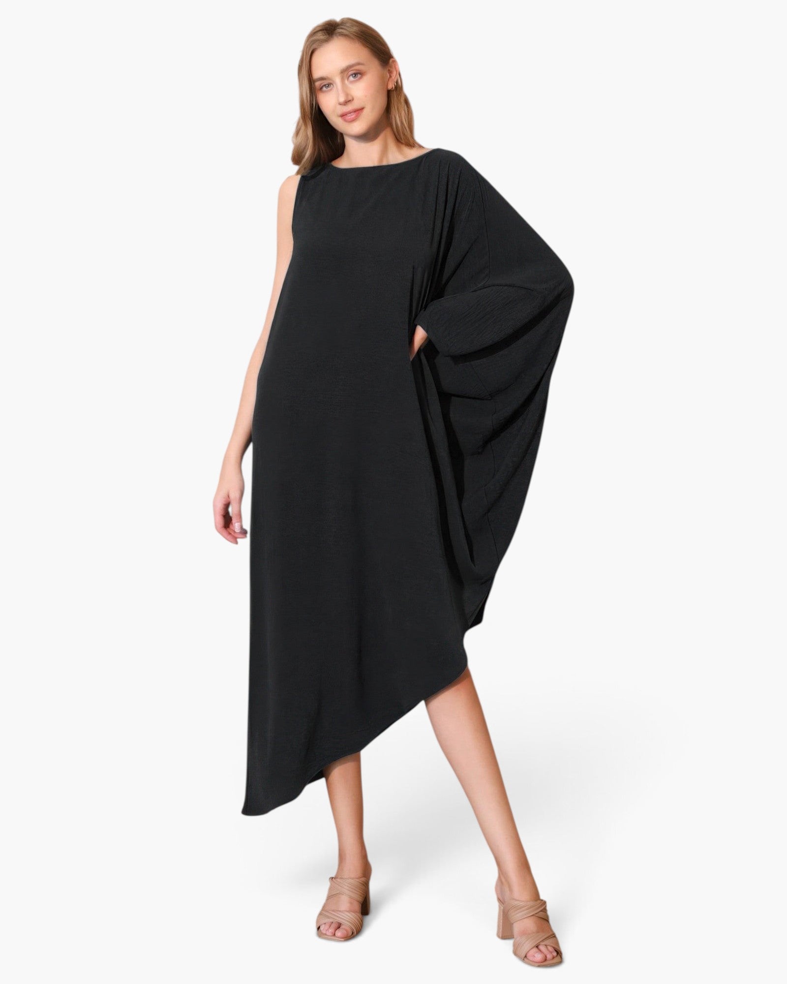 Beach Rose Co. black matte crepe one-sleeve dress with an asymmetrical hem worn by a model in beige heels.