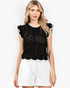 Beach Rose Co. black open-knit top with white contrast trim, ruffled cap sleeves, and a scalloped hem on a model.