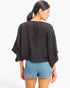 Beach Rose Co. black oversized top with loose sleeves and a relaxed drape worn by a model with blue denim shorts