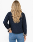 Beach Rose Co. black quilted jacket with leopard print cuffs worn by a woman with long blonde hair, back view.