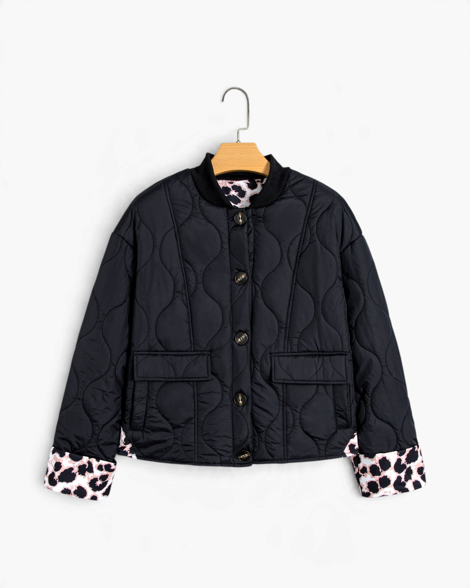 Beach Rose Co. black quilted jacket featuring curved stitching, button front, and leopard-print turn-back cuffs.
