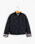 Beach Rose Co. black quilted jacket featuring curved stitching, button front, and leopard-print turn-back cuffs.