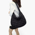 Beach Rose Co. black quilted nylon padded crossbody bag worn over the shoulder by a woman in a white blazer