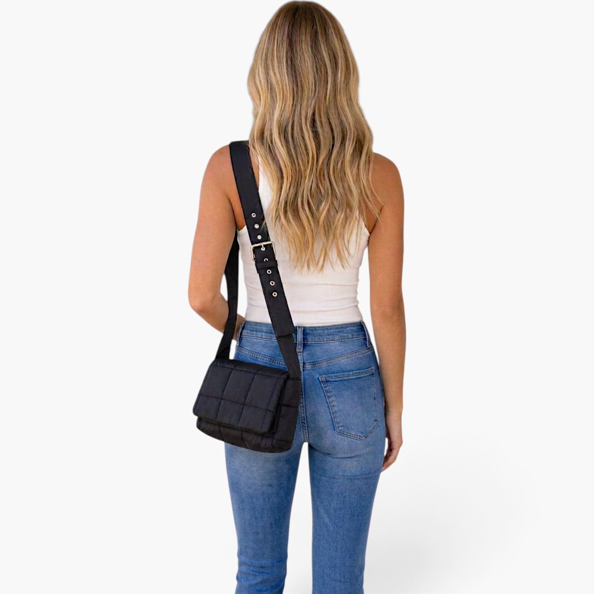 Beach Rose Co. black quilted puffer crossbody bag with wide adjustable strap worn by a woman in jeans and white top.