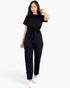 Beach Rose Co. black rib knit jumpsuit with a tie waist, short sleeves, and a relaxed fit worn by a woman.