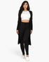 Beach Rose Co. black ribbed long cardigan and leggings set worn by a model with a white crop top and slip-on shoes