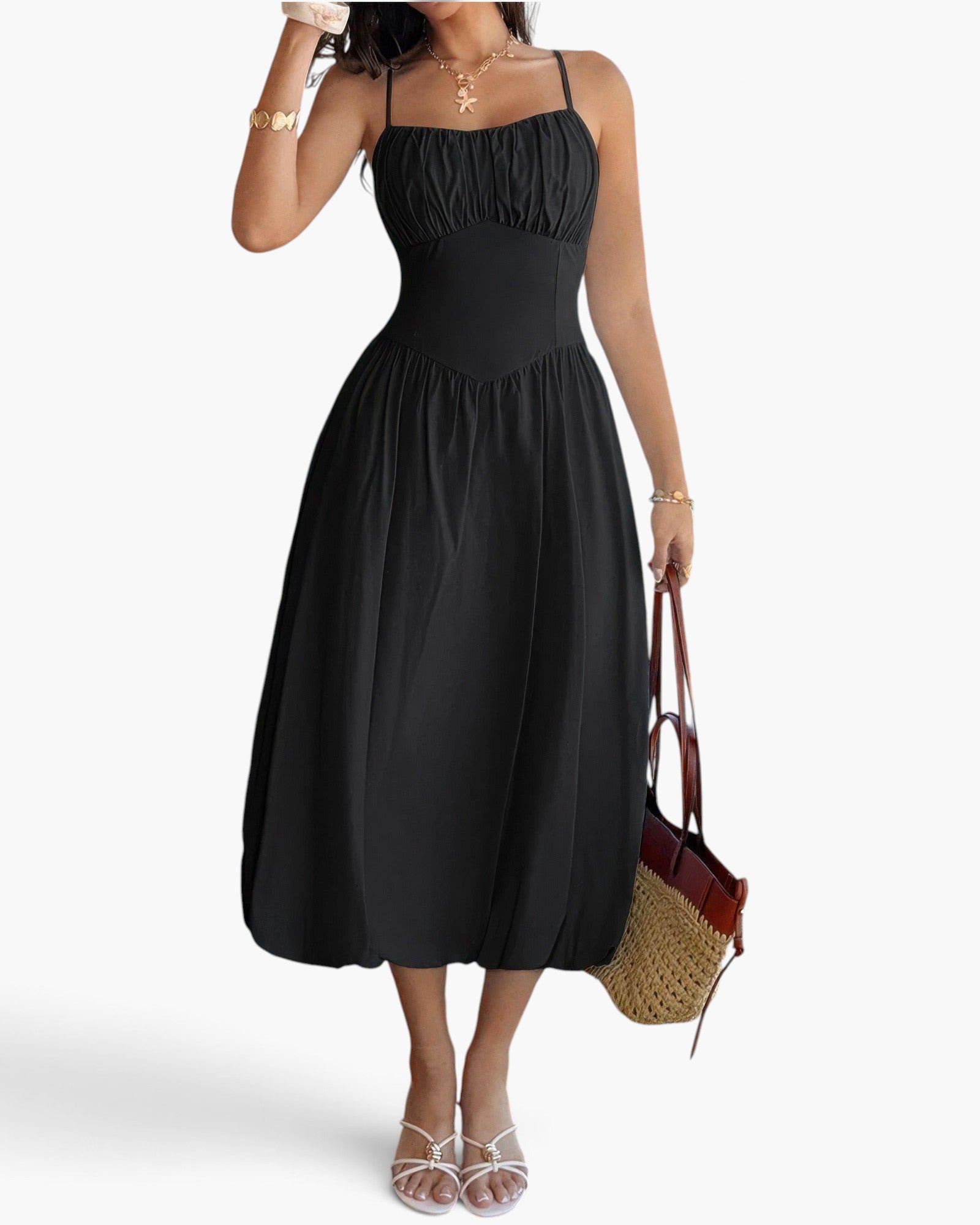 Beach Rose Co. black sleeveless A-line dress with a ruched bust, worn by a model with a straw tote bag and sandals.